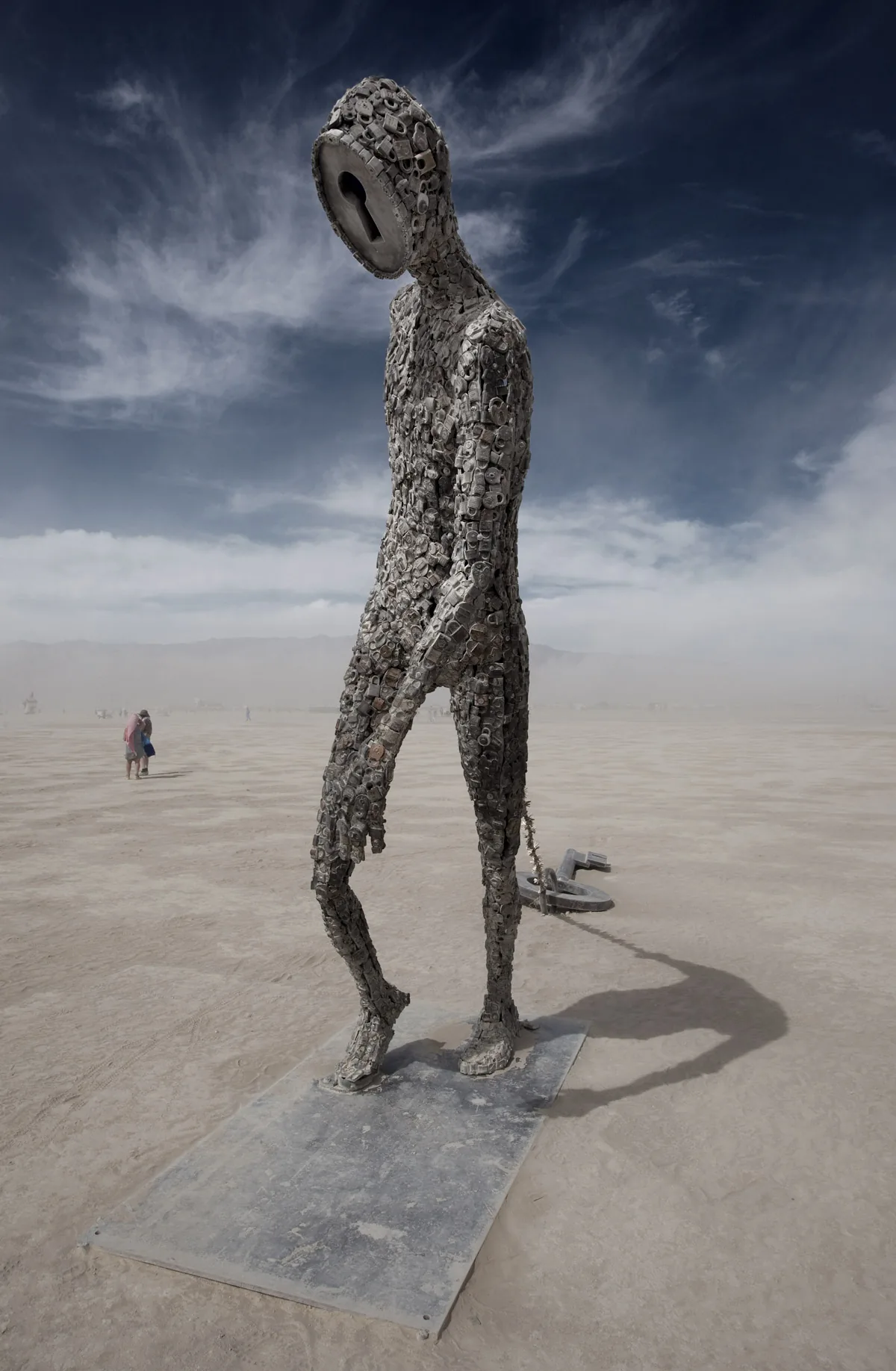 A tall, thin metal sculpture of a walking figure on the playa