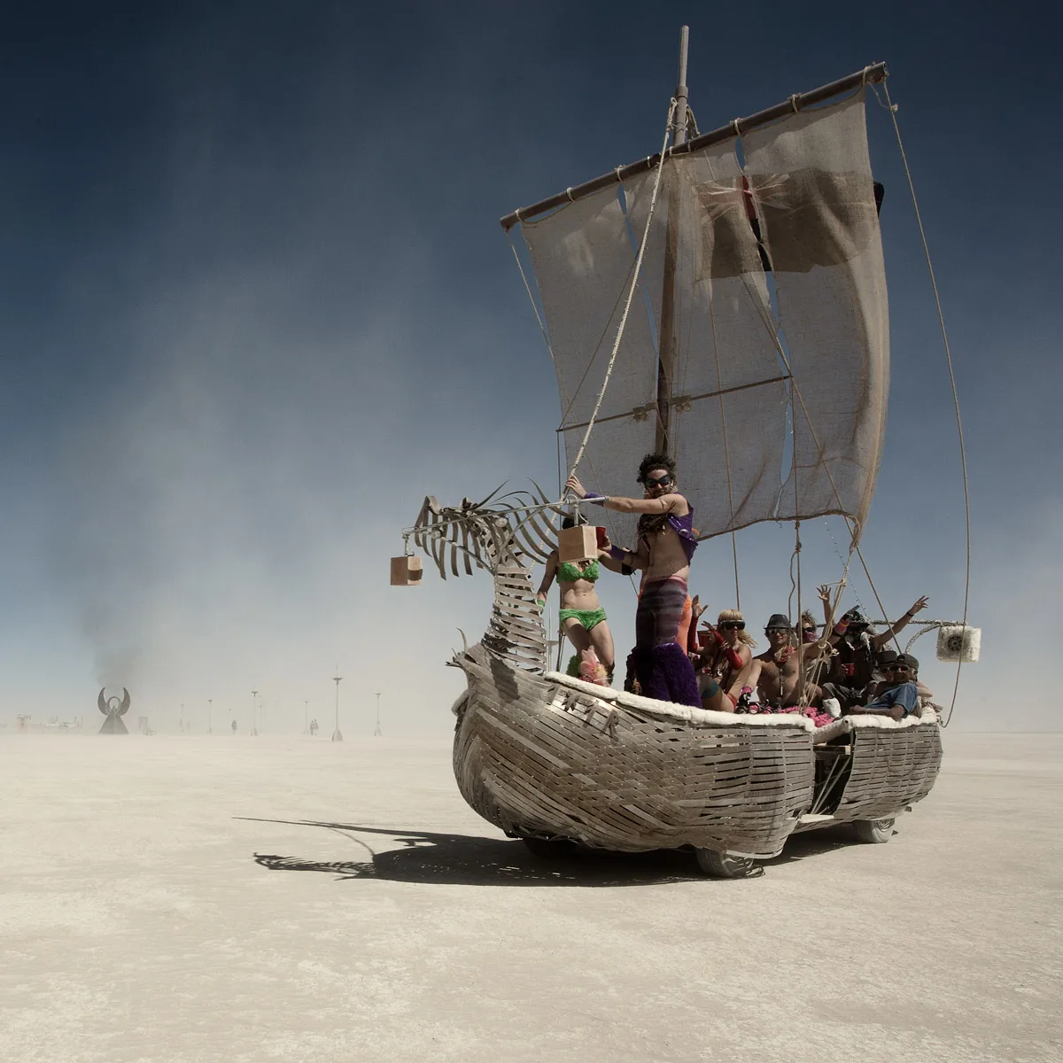 A sailboat art car full of people crossing the playa