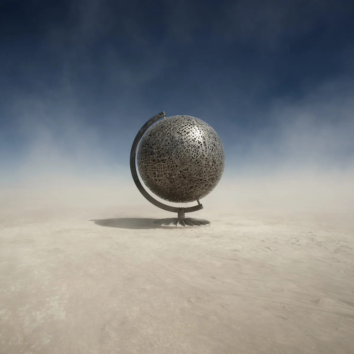 A large metal globe sculpture alone on the playa