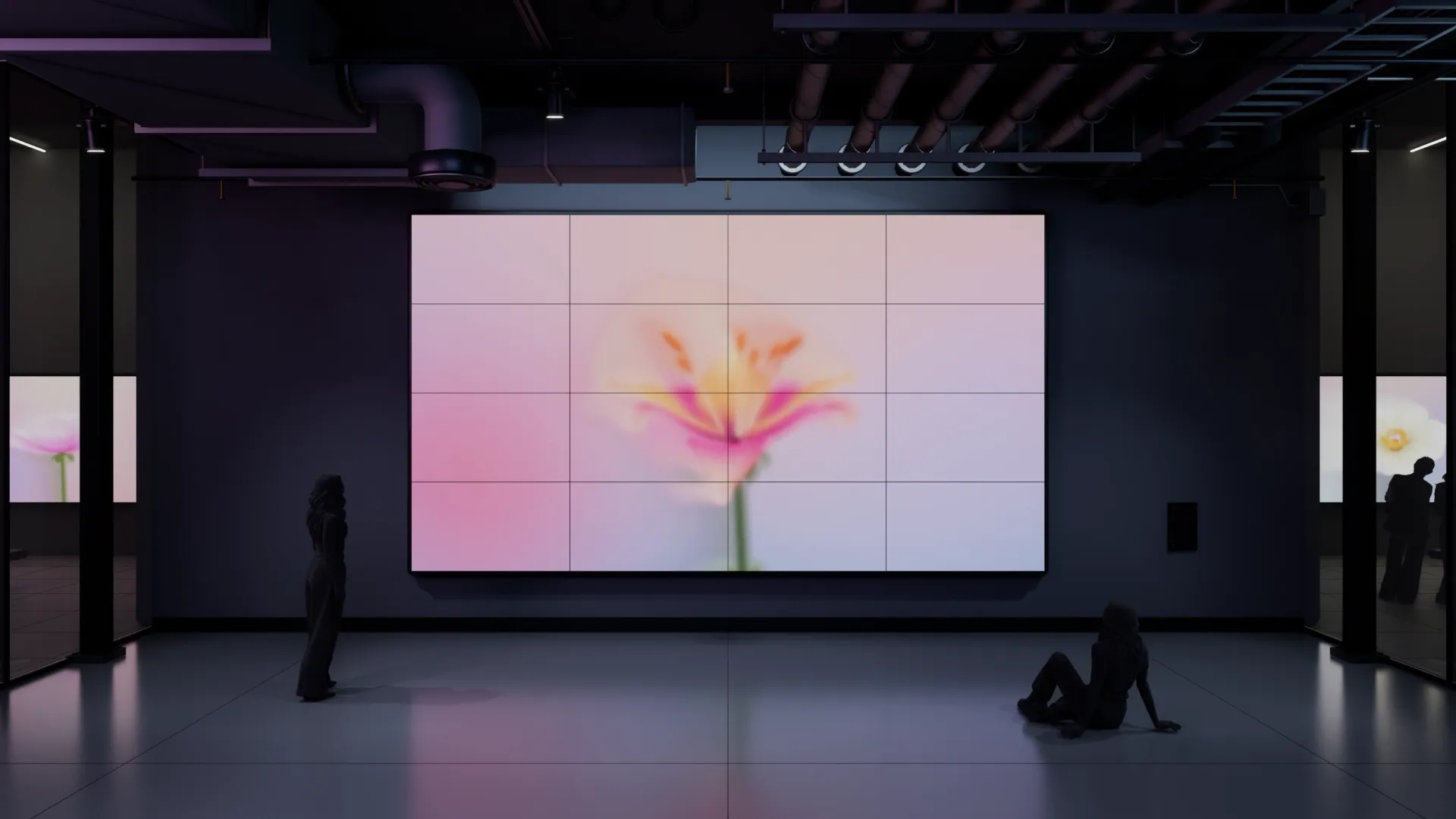 A dark gallery in Unreal Engine with a 4 x 4 video wall showing a pink lily, two visitors in silhouette, one standing and one sitting on the floor
